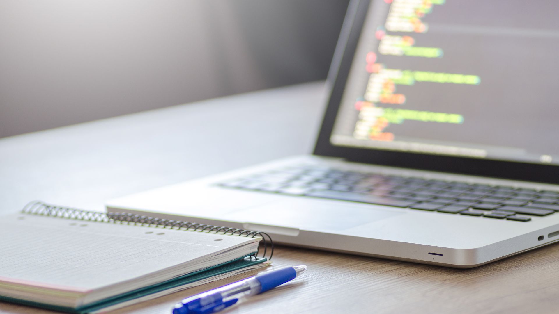 Photo of a laptop and notepad on a desk